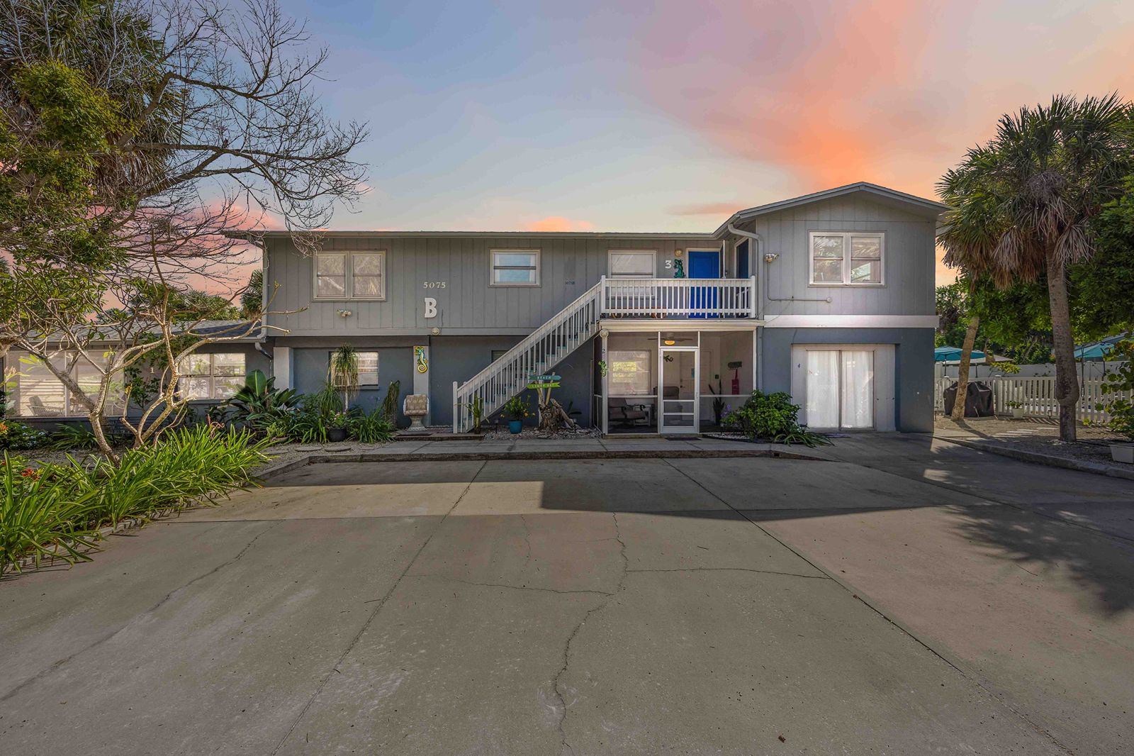 Gecko House at sunset, showing the two-story building with exterior stairs and guest parking