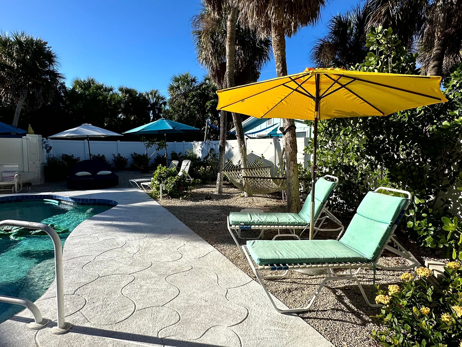 Pool loungers under a yellow umbrella at Gecko House