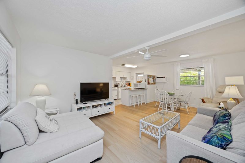 Green Gecko open living and dining area with sofa and television at Gecko House, Manasota Key