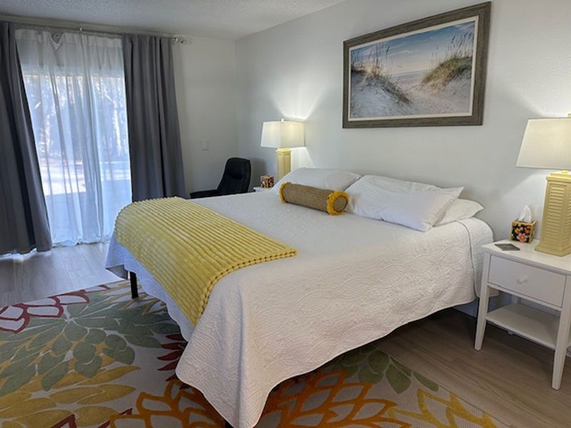 Yellow Gecko studio bed with yellow throw and framed beach artwork at Gecko House, Manasota Key